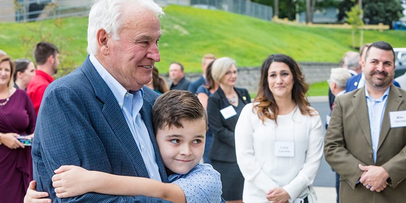Tom Golisano hugging a young boy at the Golisano Autism Center.