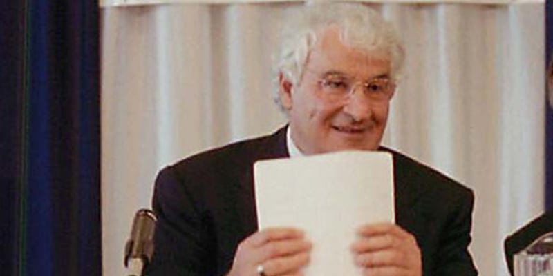 Tom Golisano wearing glasses and holding papers.