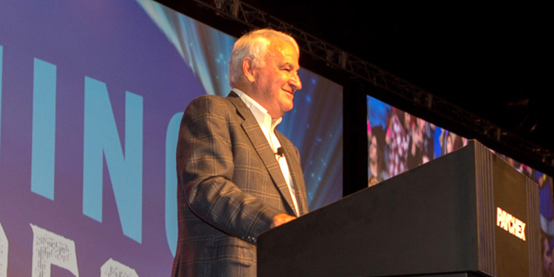 Tom Golisano at a podium speaking at a Paychex event