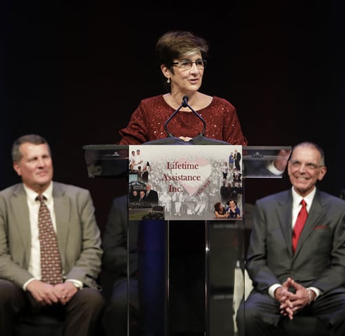 Ann Costello speaking at a podium at the Lifetime Assistance Inspiration Awards