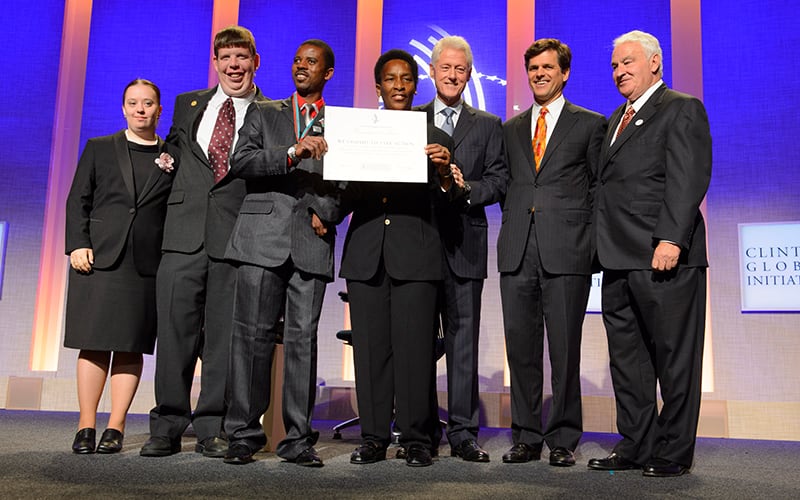 President Clinton, Tim Shriver, Tom Golisano and others pose for a photo on a stage