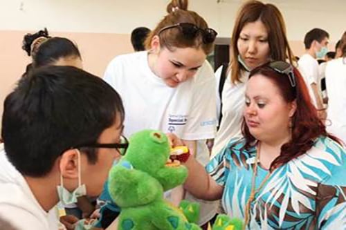 Group of women practice a health examination on a stuffed animal.