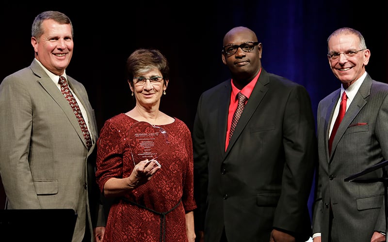 Ann Costello posing for a photo with a group of people at the Lifetime Assistance Inspiration Awards