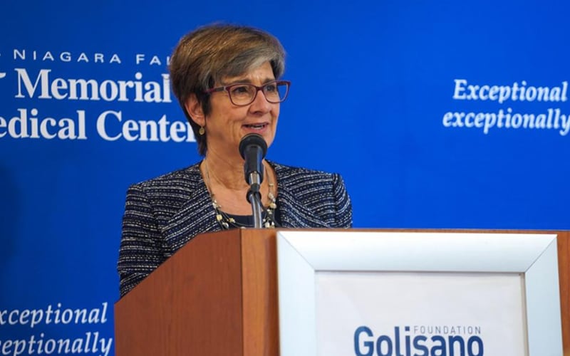 Ann Costello speaking at a podium.