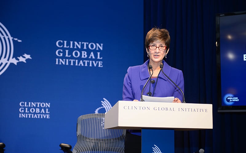 Ann Costello speaking at a podium at the Clinton Global Initiative Annual Meeting