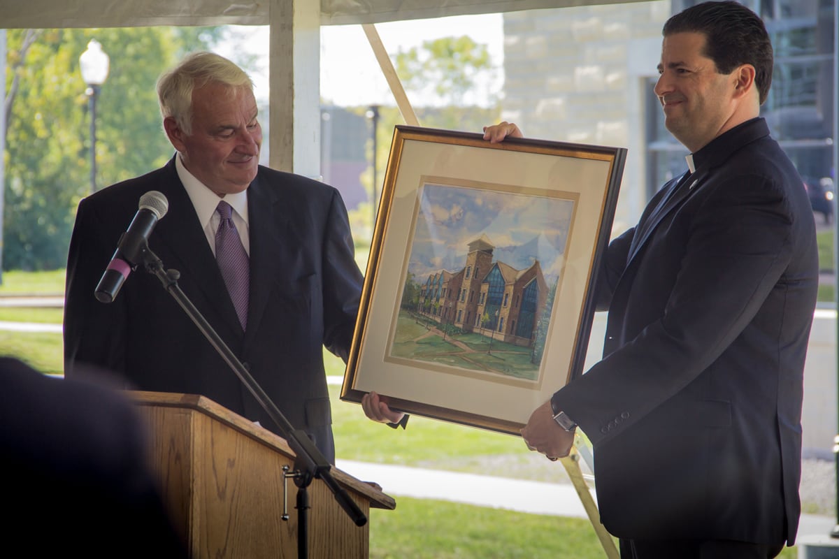 Tom Golisano and Father Maher hold a painting of the Golisano Center for Integrated Sciences building