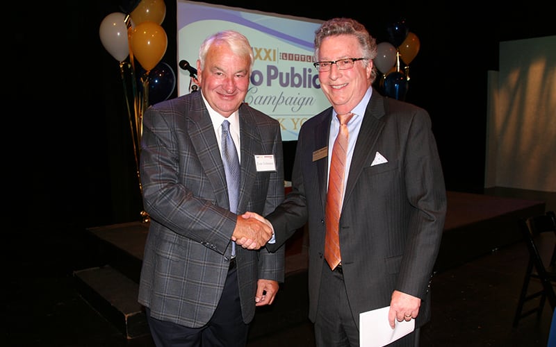Tom Golisano and Norm Silverstein shake hands at a WXXI event