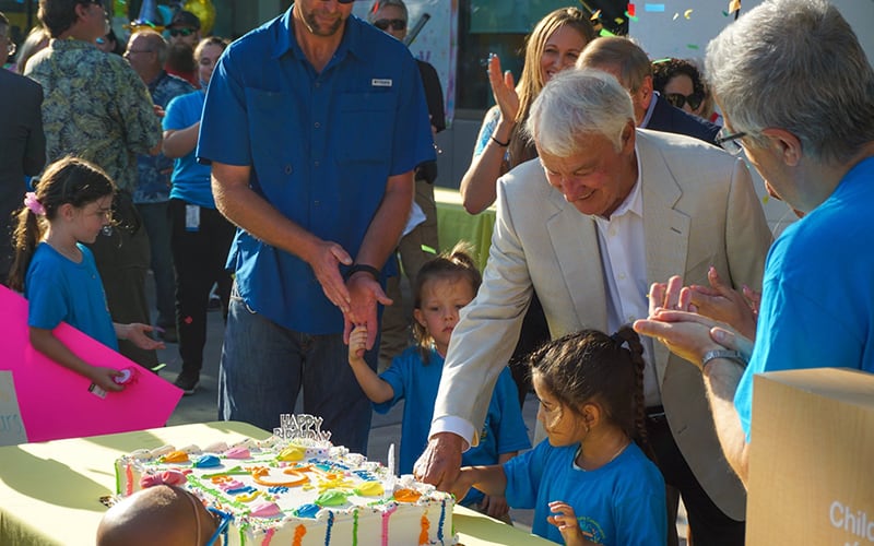 Tom Golisano cutting cake with a group of children at the Golisano Children's Hospital of Southwest Florida's five year celebration.